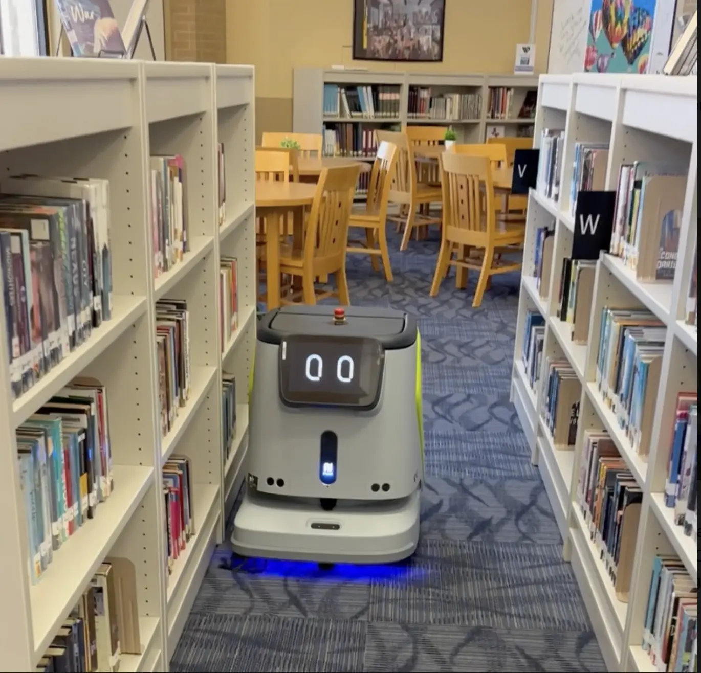 A RoboSmart cleaning robot with glowing blue lights running down a library aisle between tall bookshelves