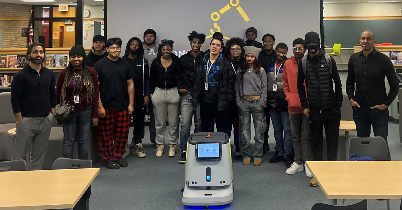 Students and an instructor gathered around a service robot in a school media center
